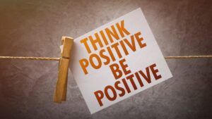 Graphic of a card stating 'Think Positive Be Positive' attached to a sting with a clothes peg to illustrate the Law of Attraction